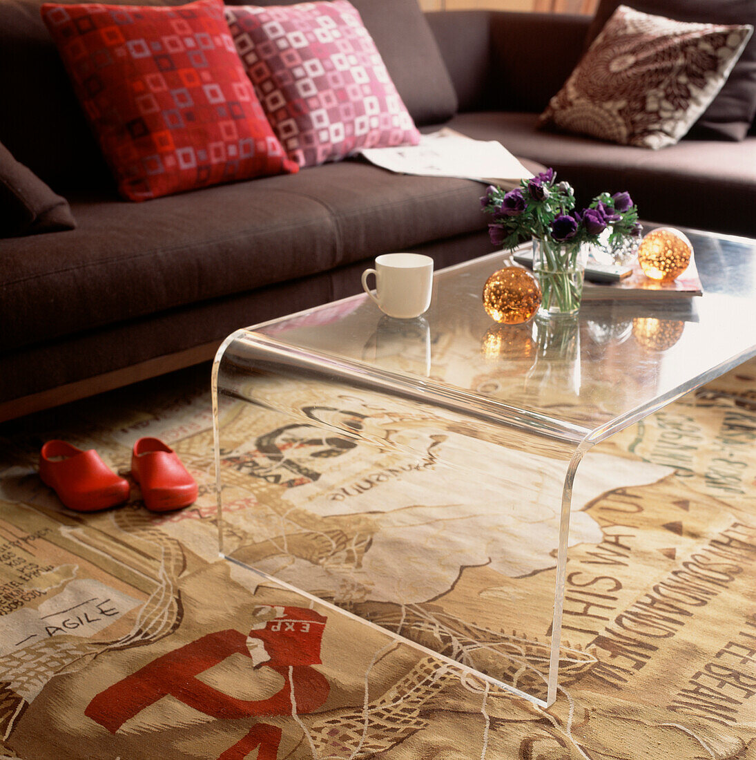 Modern style living room with brown sofa with scatter cushions Perspex coffee table and patterned carpet