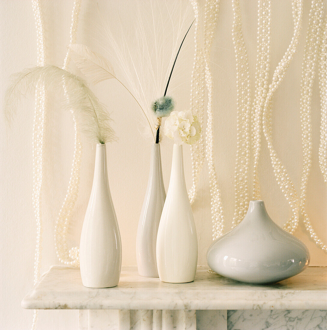 Detail of white vases and Christmas decorations on a marble mantelpiece