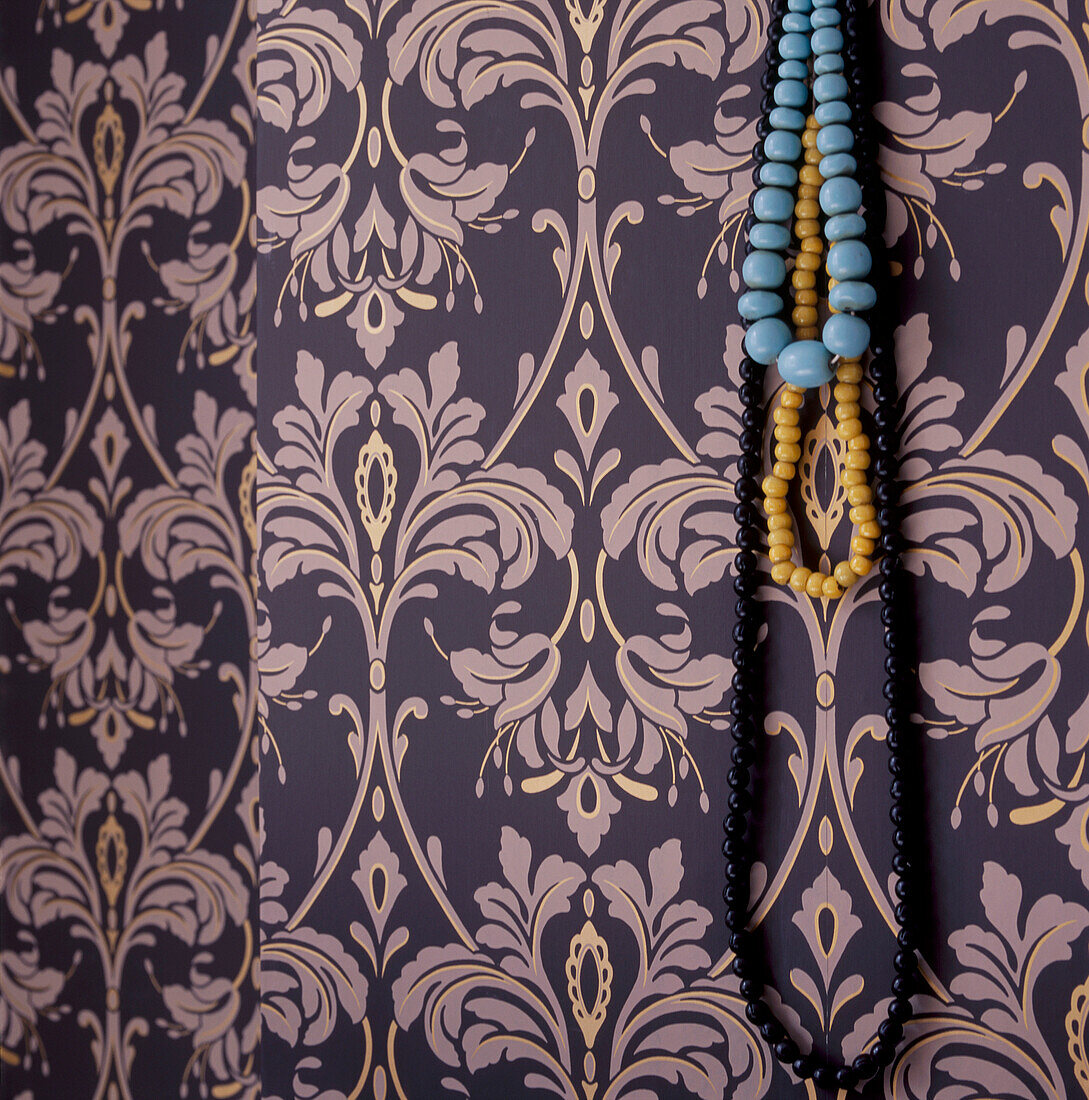 Patterned wallpaper with jewellery hung on a hook