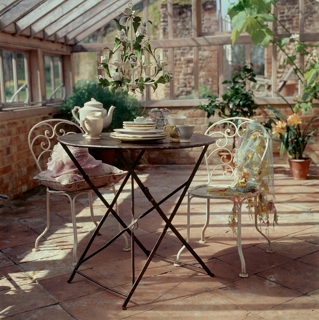 Metal garden table and chairs in a period glass conservatory with tableware