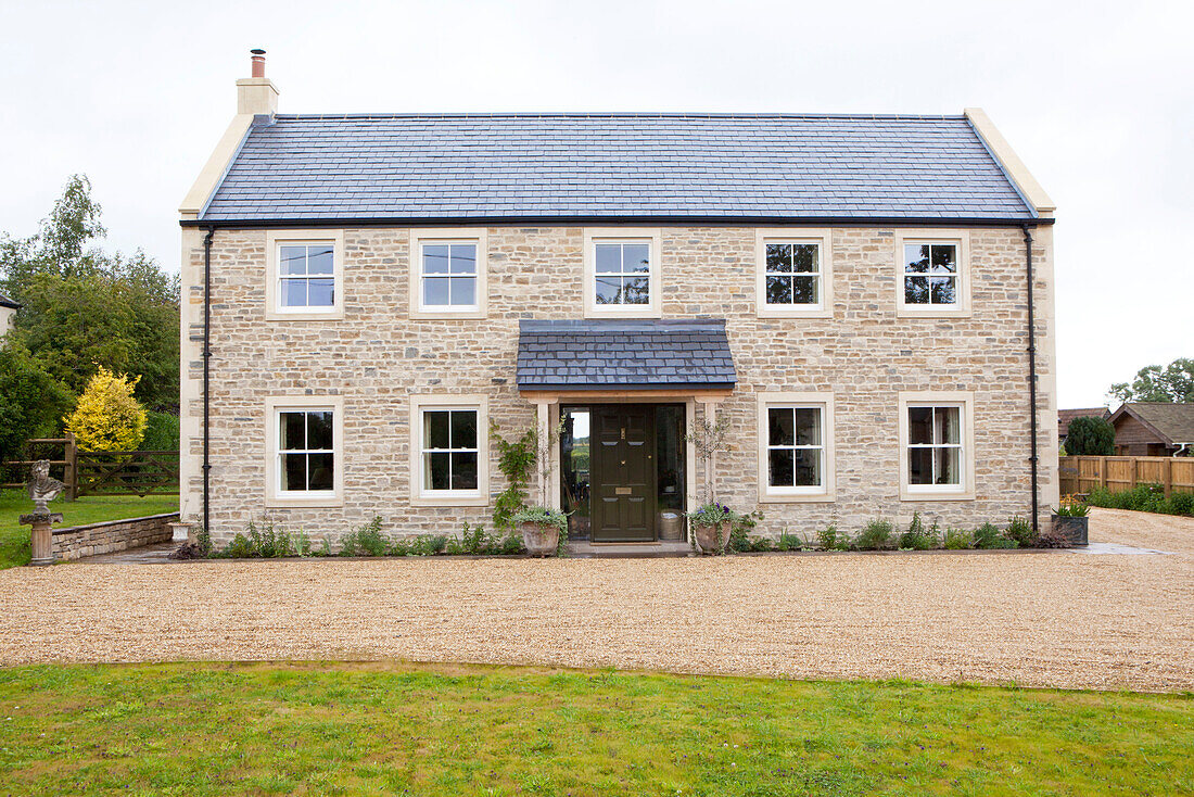 Gravel driveway and stone facade of detached Wiltshire country house England UK
