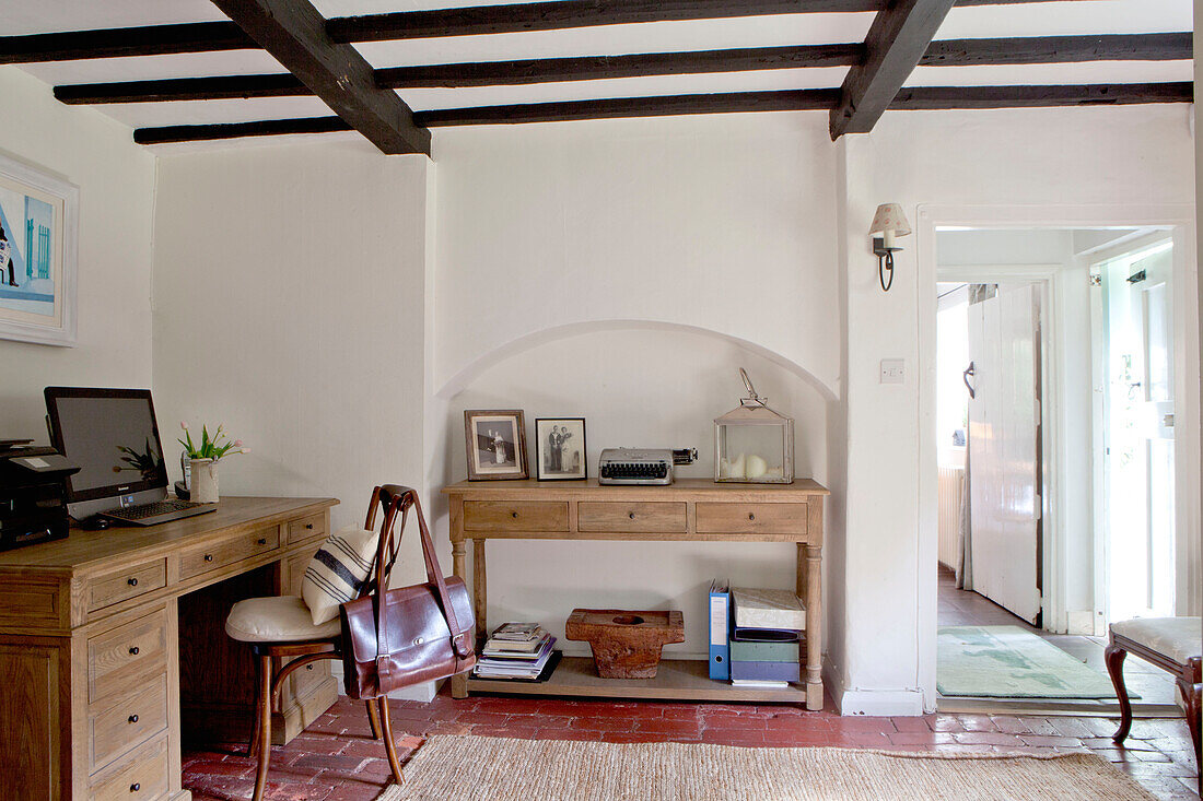 Brown satchel on chair at desk with computer screen in beamed Surrey cottage England UK