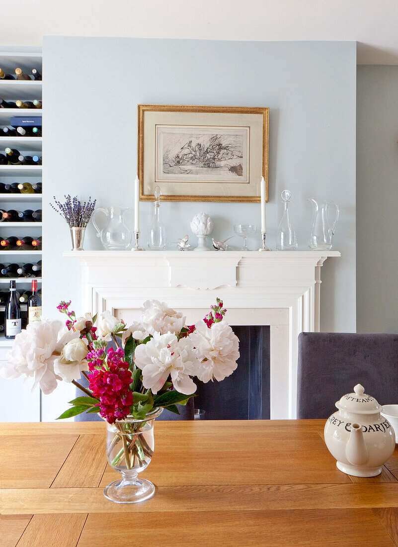 Cut flowers and teapot on wooden dining room table in contemporary Chelsea home London UK