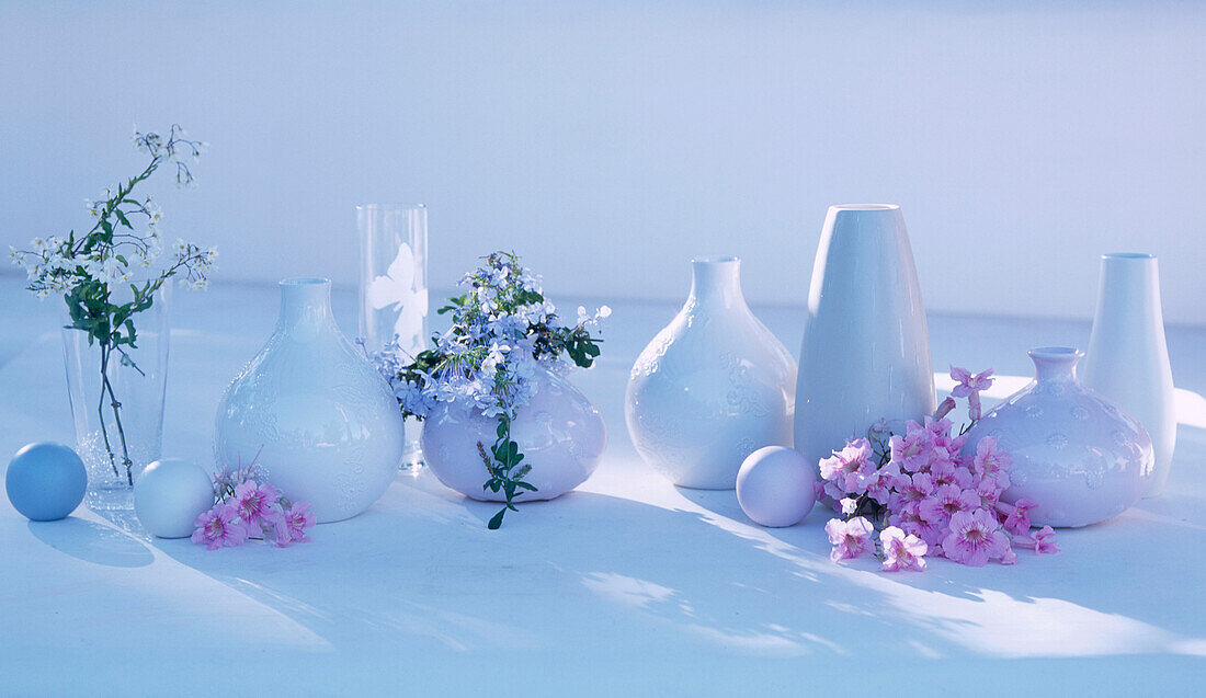 Still life of ceramic vases and homeware on a garden table with flower display