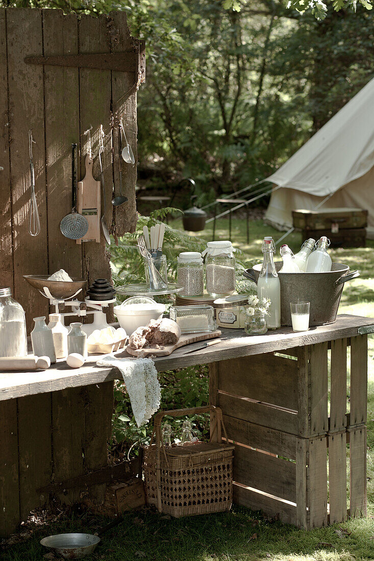 Baking equipment on makeshift table in garden with pitched tent, UK