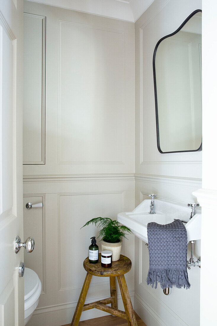 Fern and soap dispenser on wooden stool in bathroom of London home UK