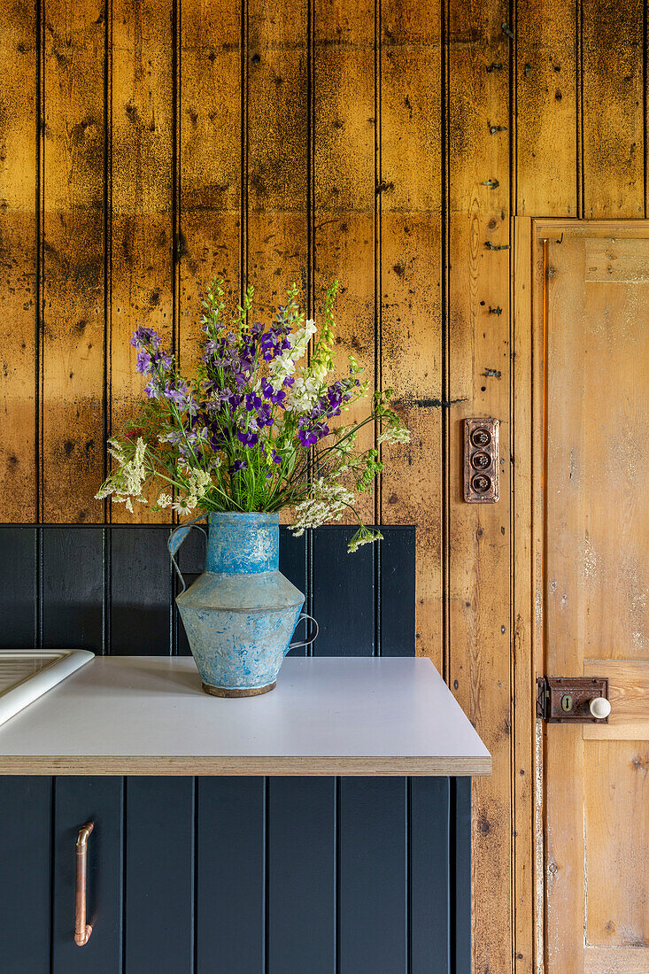 Schnittblumen in Vase auf Arbeitsplatte in holzverkleideter Scheune in Cirencester, Gloucestershire, Großbritannien