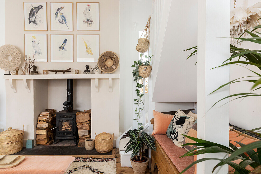 Japanische Drucke über dem Holzofen mit hängenden Körben in einem Cottage in Devon