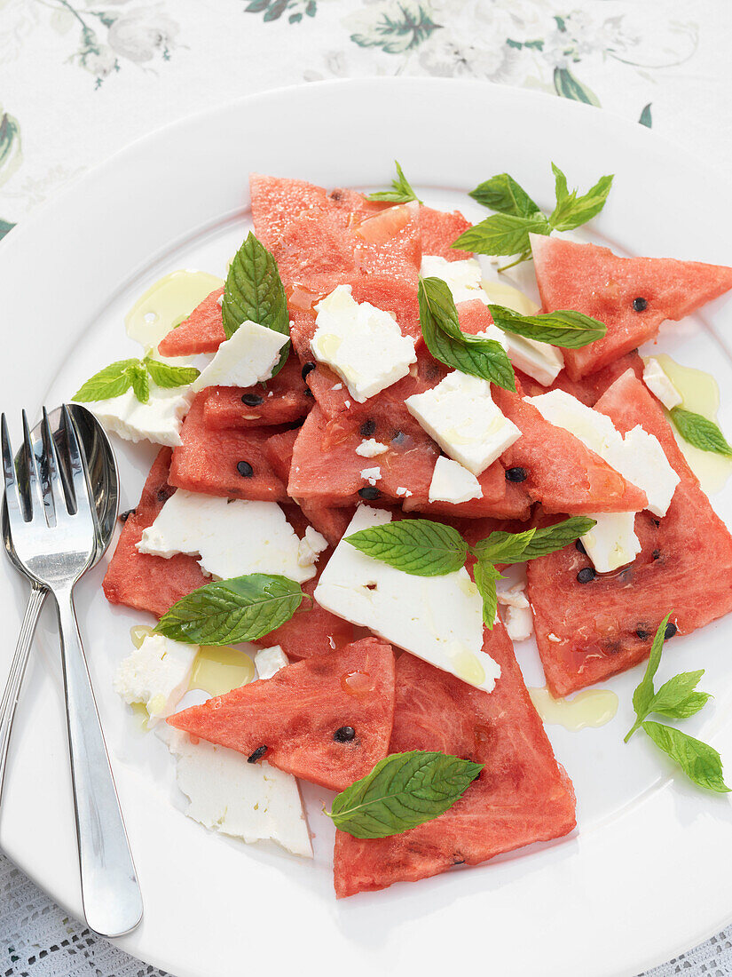 Aufgeschnittene Wassermelone und Käse mit Gabel und Löffel auf Teller Derwent Water, Cumbria, England UK