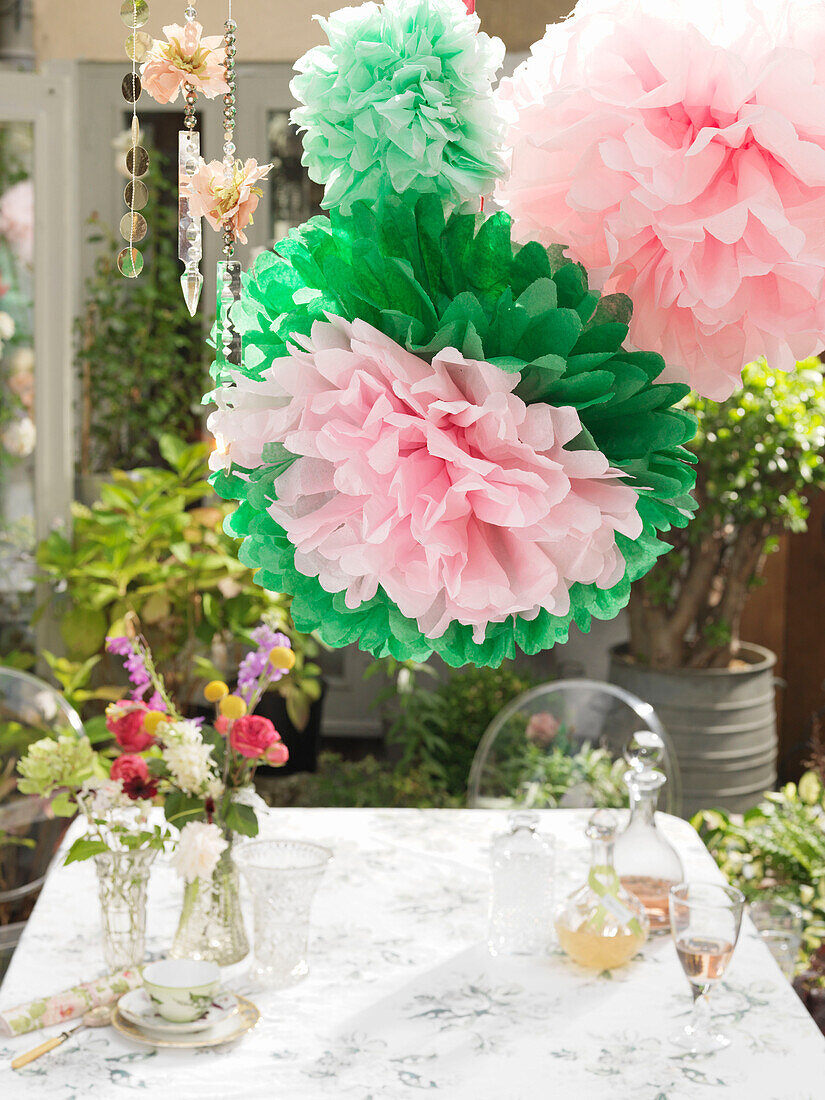 Paper flowers above garden table with glasses of cut flowers and decanters Derwent Water, Cumbria, England UK