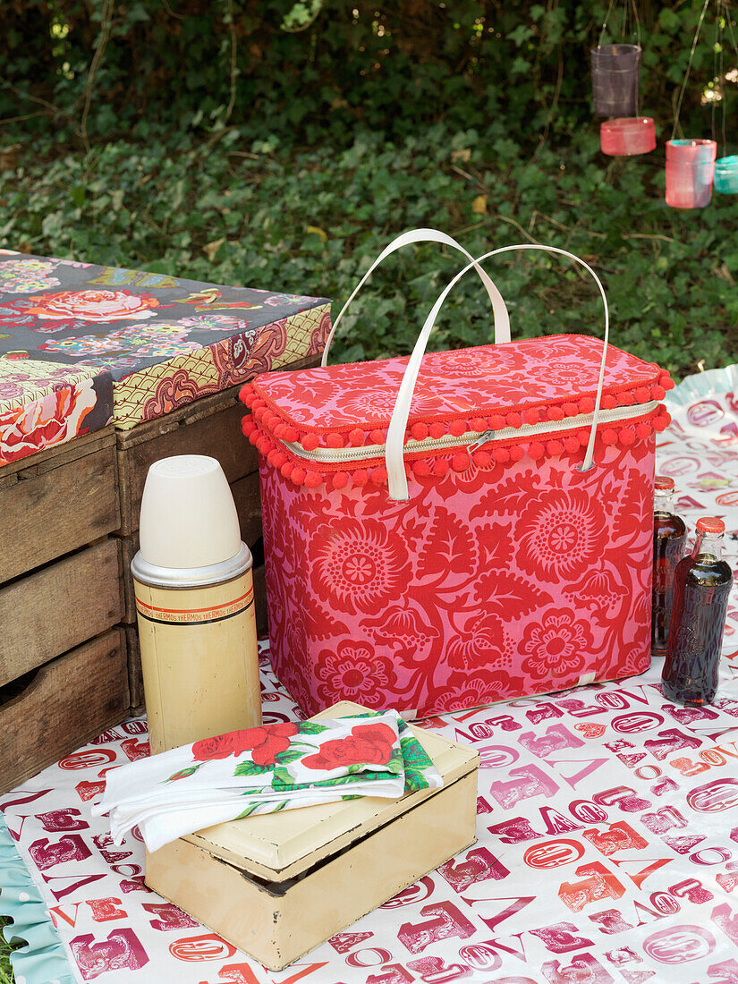 Coolbox and crates with flask on picnic blanket London England UK