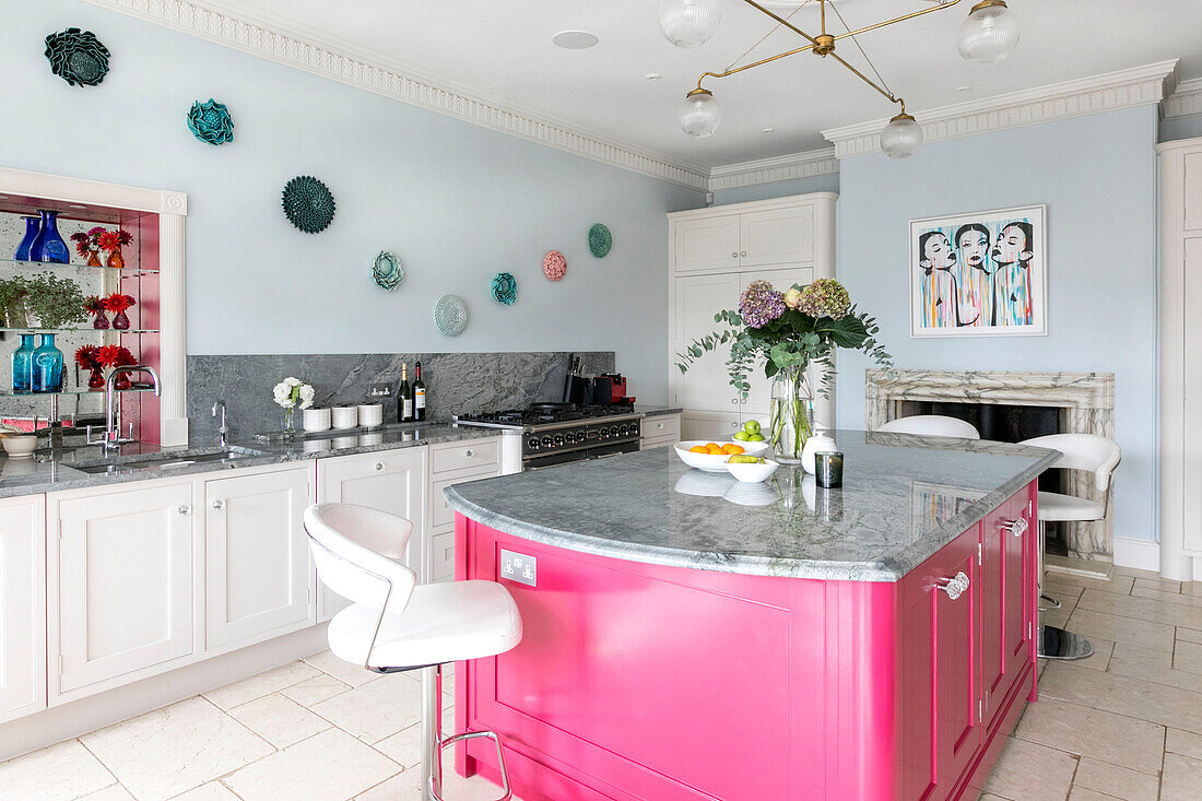 Bright pink island unit in light blue modernised kitchen of Georgian Grade II listed Surrey home UK