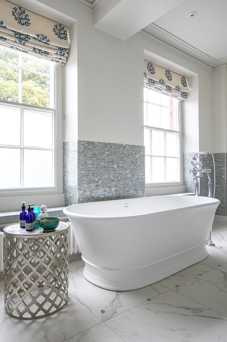 Freestanding bath in window of silver tiled bathroom in Georgian Grade II listed Surrey home UK