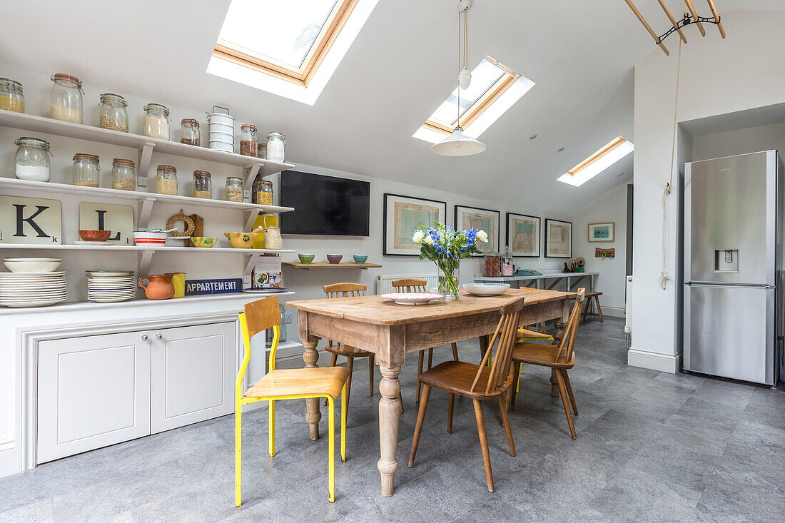 Dried food storage with wooden table and chairs below skylight windows in Reading kitchen Berkshire England UK