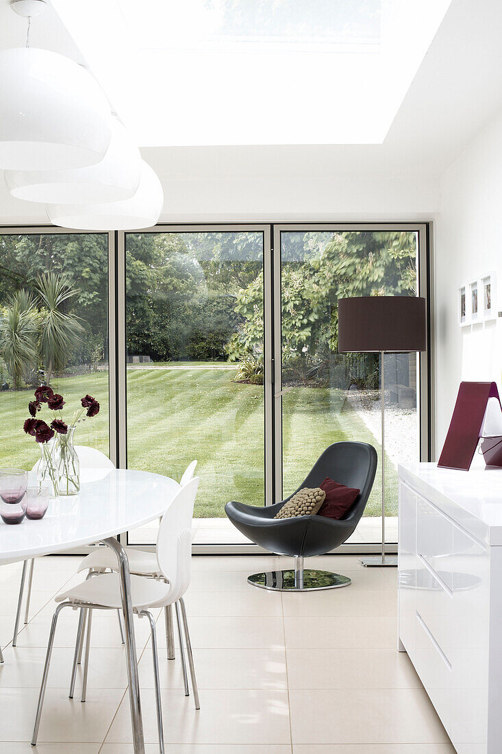 Kitchen extension with black leather chair and view through doors to back garden