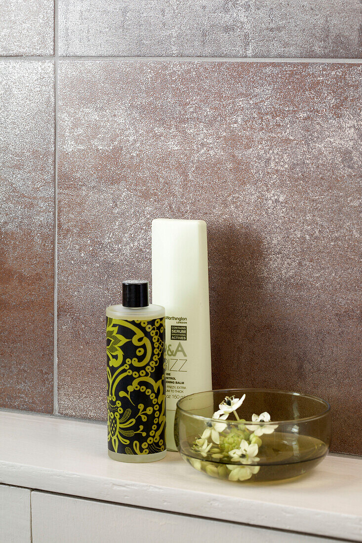 Toiletries and cut flower in bowl in London bathroom England UK