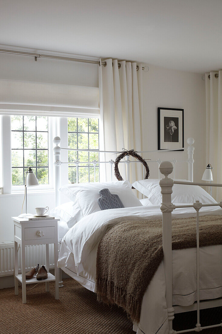Weiß gestrichenes Schlafzimmer mit Bleiglasfenstern in einem Haus auf der Isle of Wight, UK