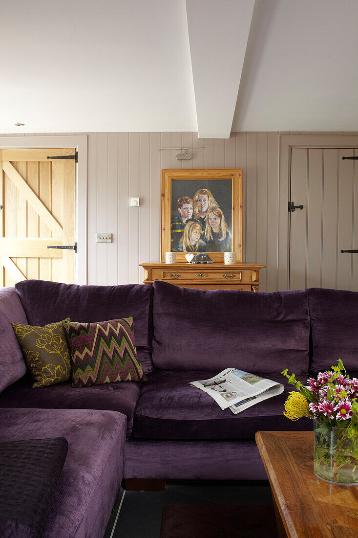 Cut flowers on coffee table with purple sofa in Somerset home England UK