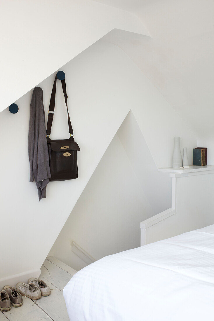 Tasche und Strickjacke hängen über den Schuhen im Schlafzimmer eines modernen Hauses am Strand von Weymouth, Dorset, UK