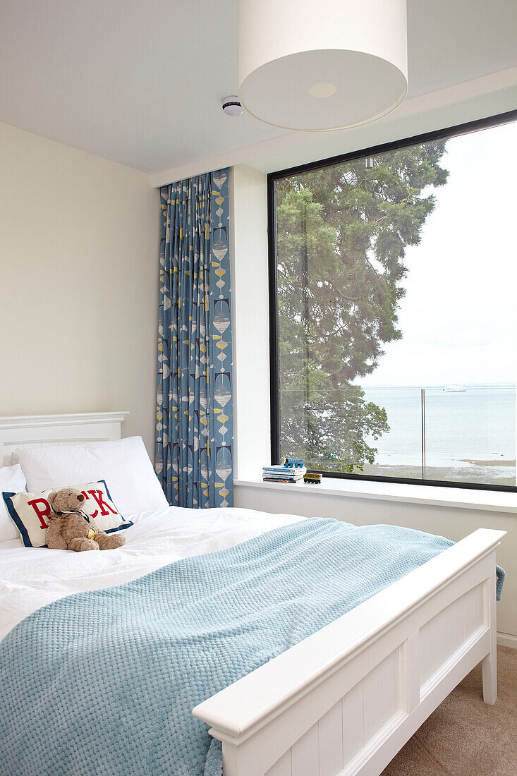 Teddybear on double bed at window in modern Isle of Wight home UK