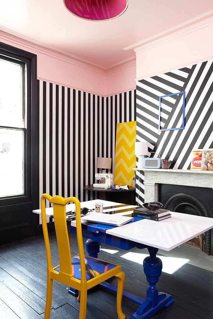 Yellow chair at blue table with black and white striped wallpaper in Hastings townhouse East Sussex England UK