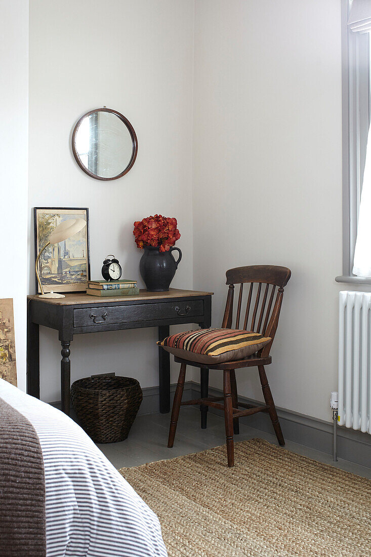 Vintage wooden chair at table with coir rug in bedroom of Brighton home East Sussex UK