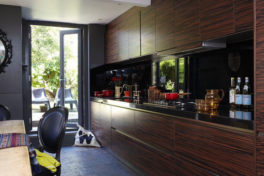 Pan on hob in wooden fitted kitchen with open back doors in London home, England, UK