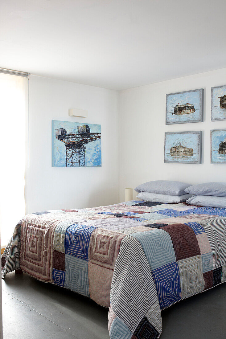 Patchwork quilt on double bed with artwork in Bembridge houseboat Isle of Wight, UK