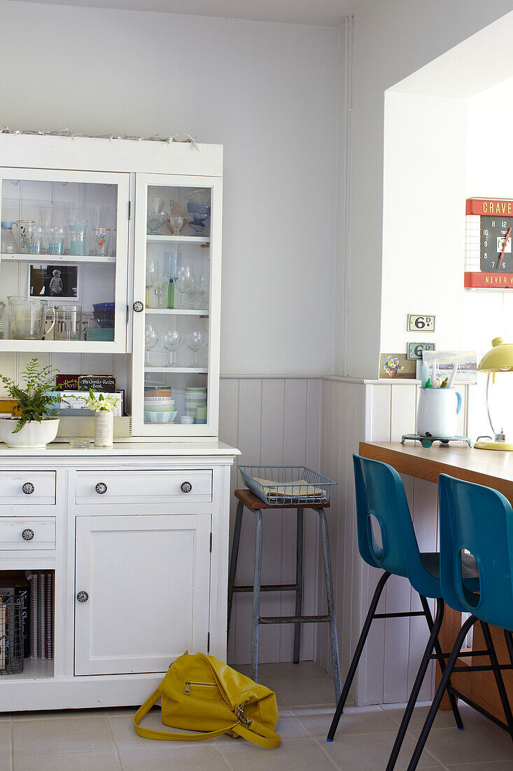 Teal barstools and yellow handbag with white painted kitchen dresser in Ryde home Isle of Wight, UK