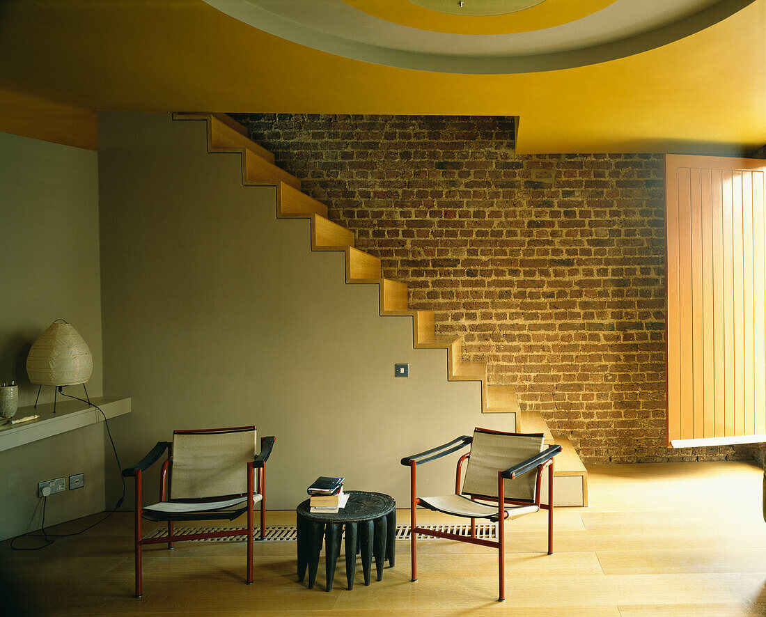Open plan living room with an open staircase and a pair of Le Corbusier style Basculant chairs