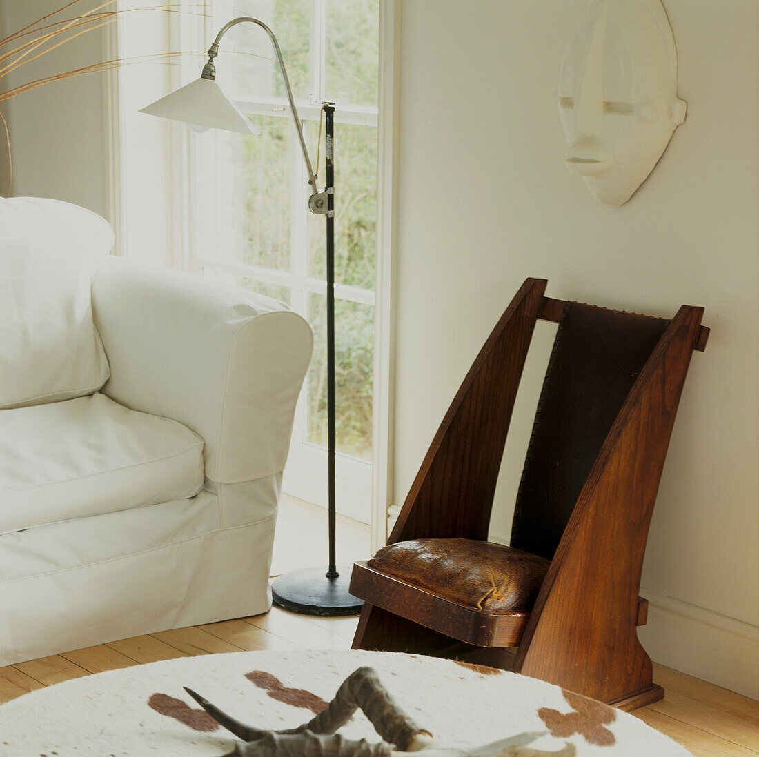 Floor lamp and vintage wooden chair in corner of white decorated living room