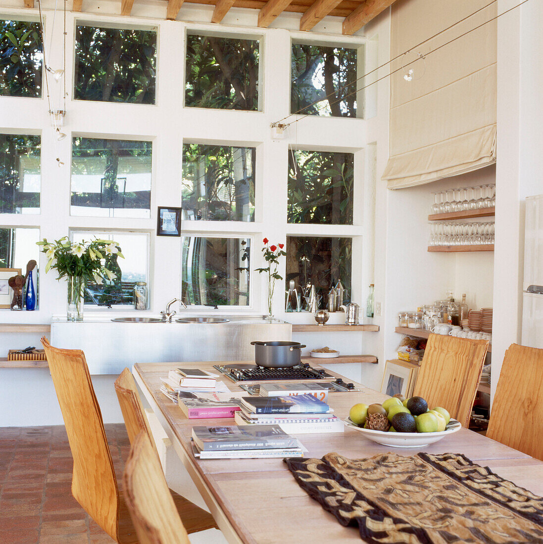 Holztisch und -stühle in einer Küche mit eingebautem Herd und doppelt hohem Fenster