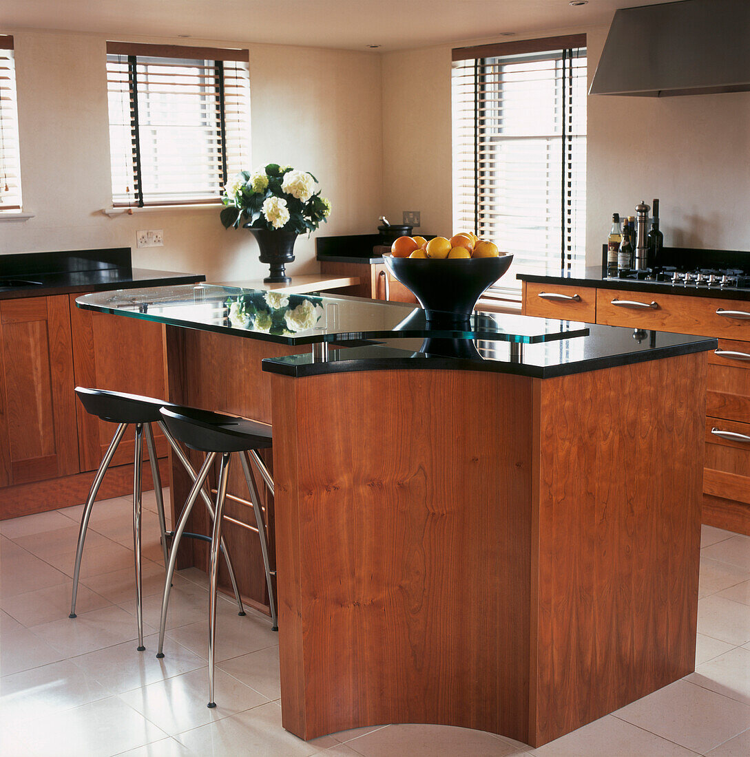 Cherry wood fitted kitchen with black granite worktops and curved kitchen island with bar stools