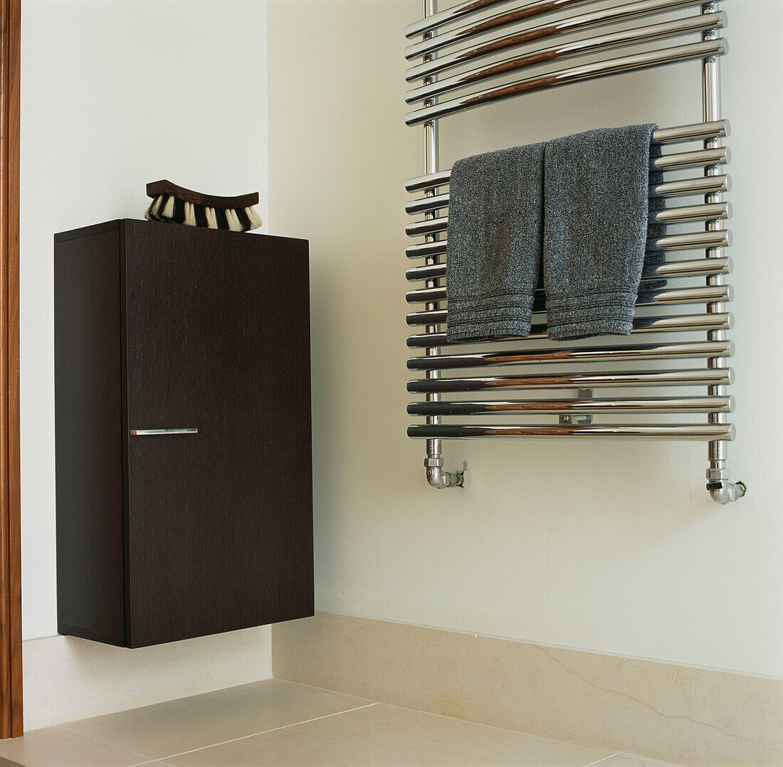 Detail of chrome heated towel rail and cabinet in bathroom