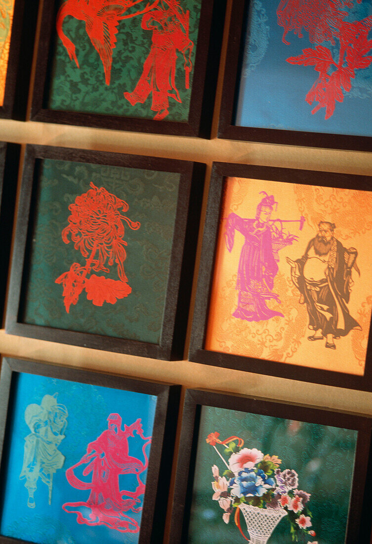 Detail of colourful framed Chinese silk fabrics with stencilled graphics