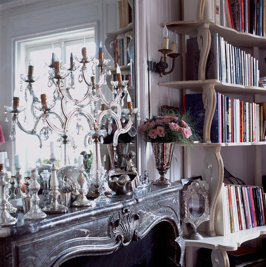 Venetian glass candelabra on ornate marble mantelpiece with curved fronted bookcase