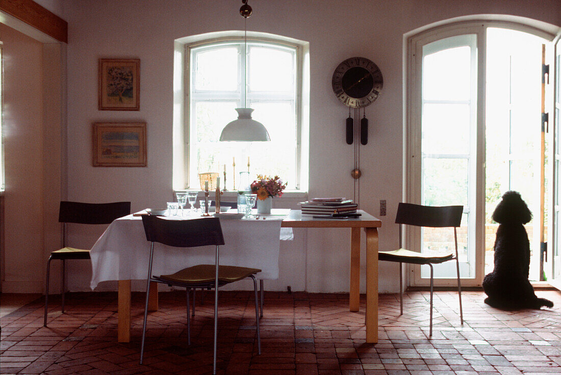 White modern country style dining room with brick floors and dining table set for lunch