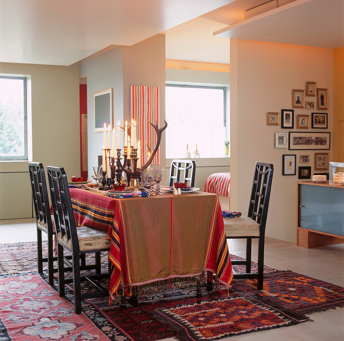 Dining table covered in Frisian fabric with stag horn candelabras and African turned candlesticks in open plan living room