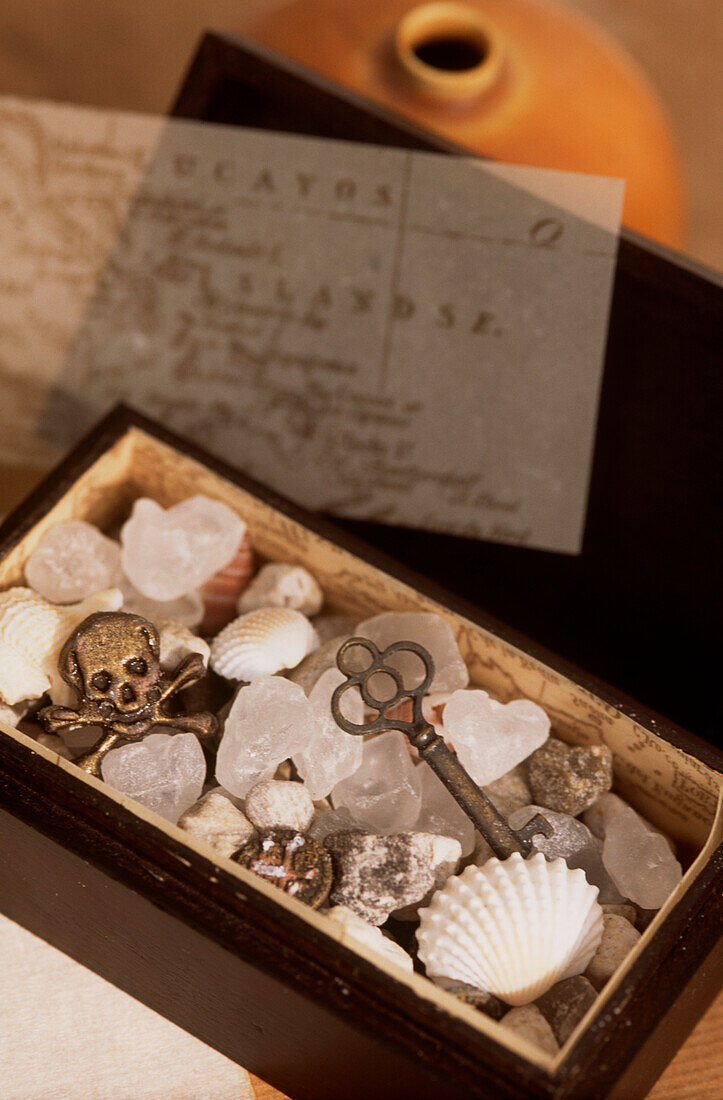 A mini treasure chest - dark wooden box filled with seashells skull and cross bones and a vintage key
