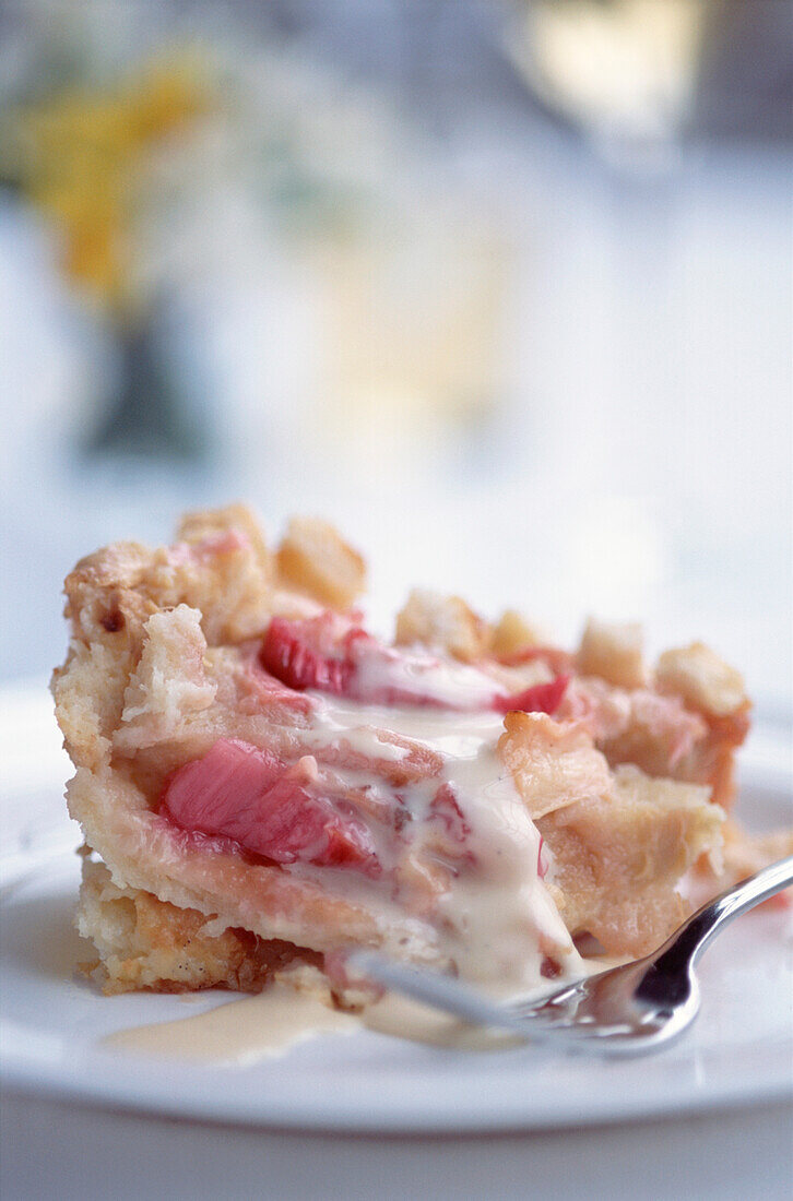 Rhabarber-Crumble mit Vanillepudding auf einem weißen Teller mit stimmungsvollem Hintergrund