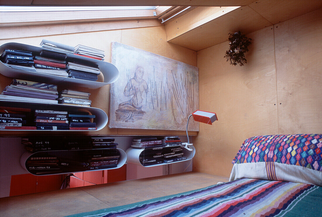 Contemporary attic room with large velux window wood panelled walls and open book shelves