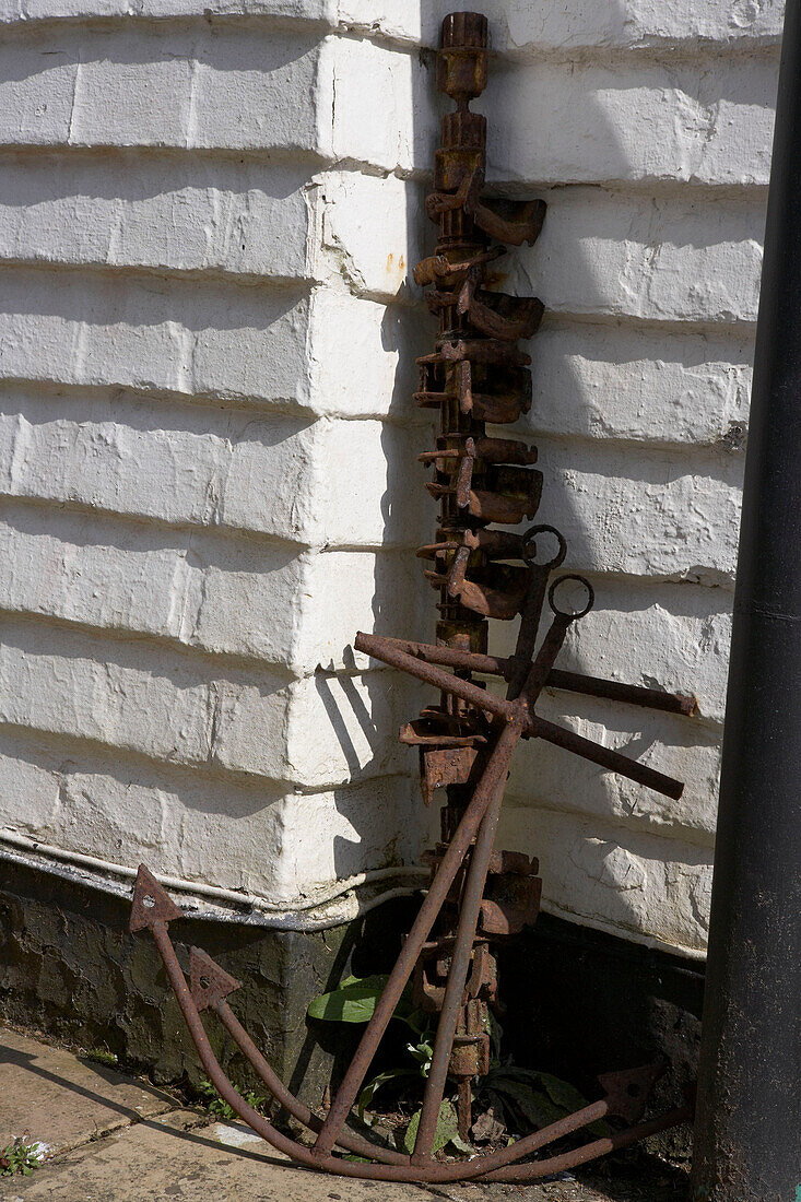 Vintage rusty anchors and metalwork beach finds leaning against exterior wall