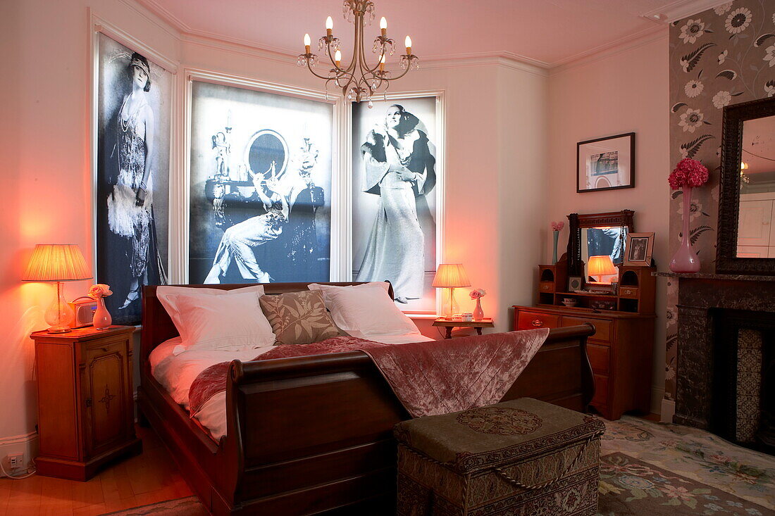 Vintage black and white artwork above double bed with lit lamps in funky London home, England, UK