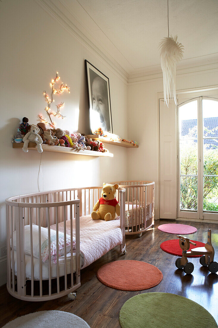 Modernes Kinderzimmer mit farbenfrohen runden Teppichen und einem großen Kinderbett