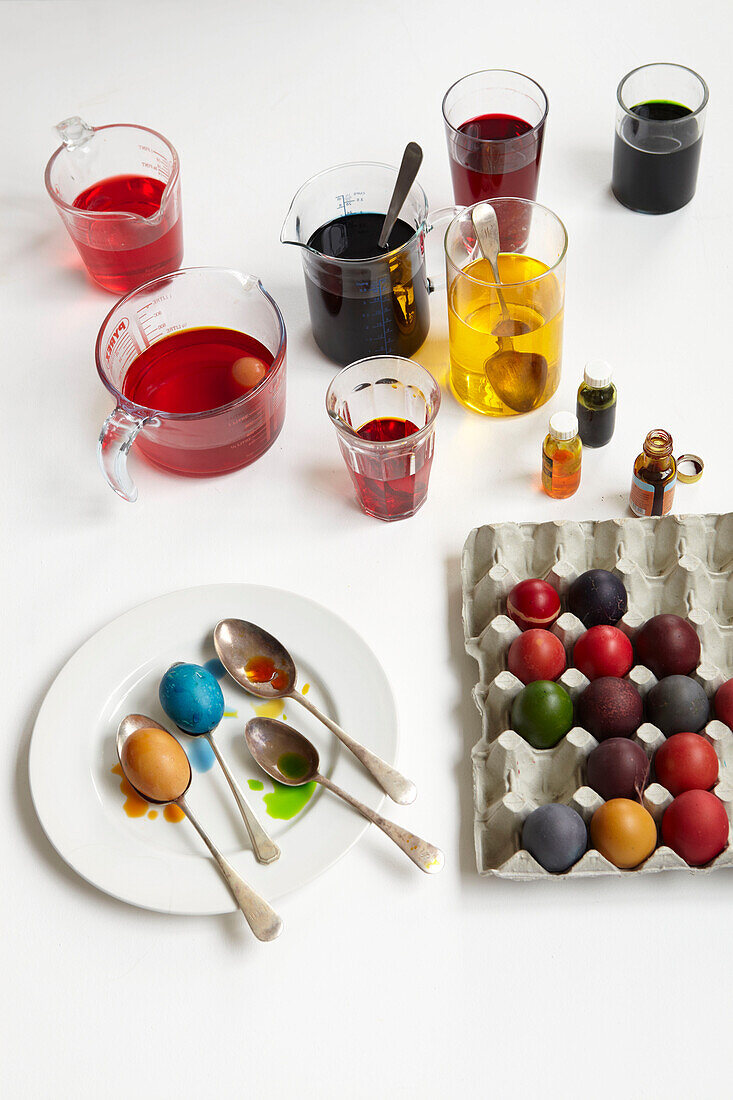 Cardboard tray of multi-coloured eggs and various pots of paint and dye