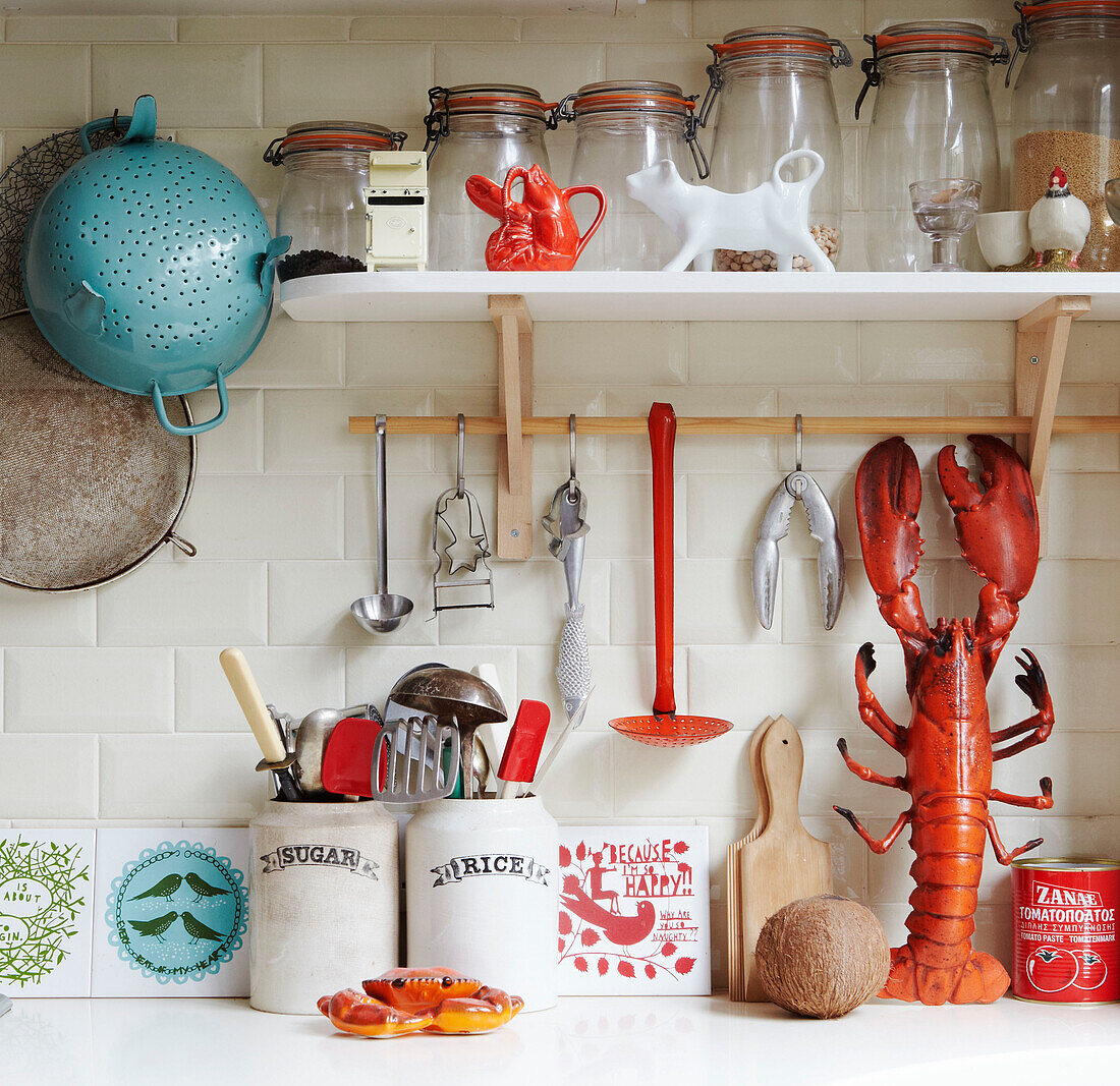 Utensils and storage jars in white tiled kitchen