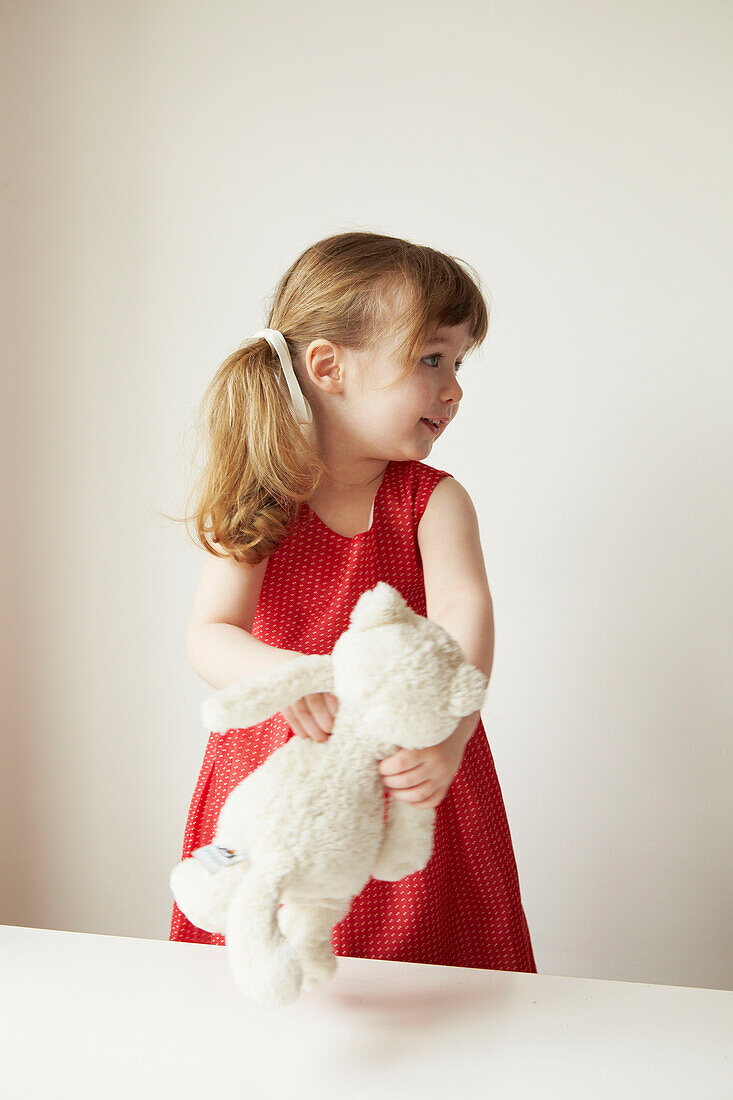 Young girl in red dress holding a teddybear