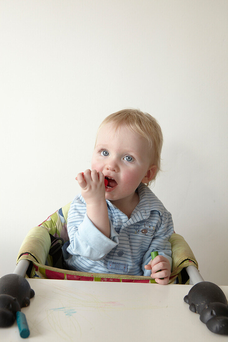 Two year old boy sits in high chair