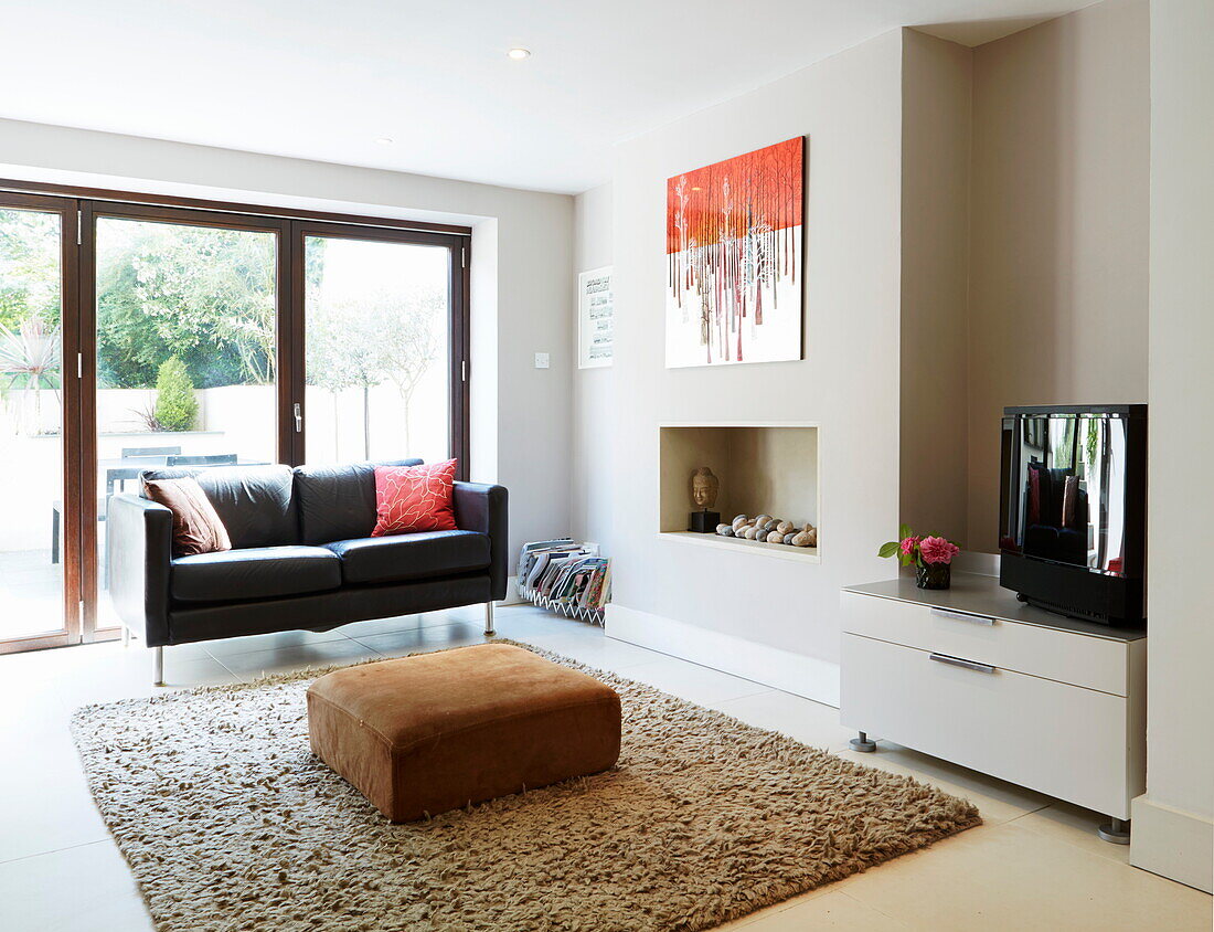 Black leather two-seater sofa in living room of London townhouse, England, UK