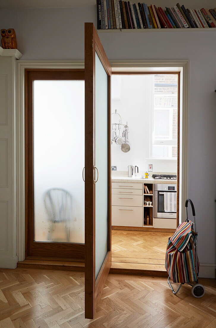 Open door with parquet floor and shopping trolley in London townhouse, England, UK